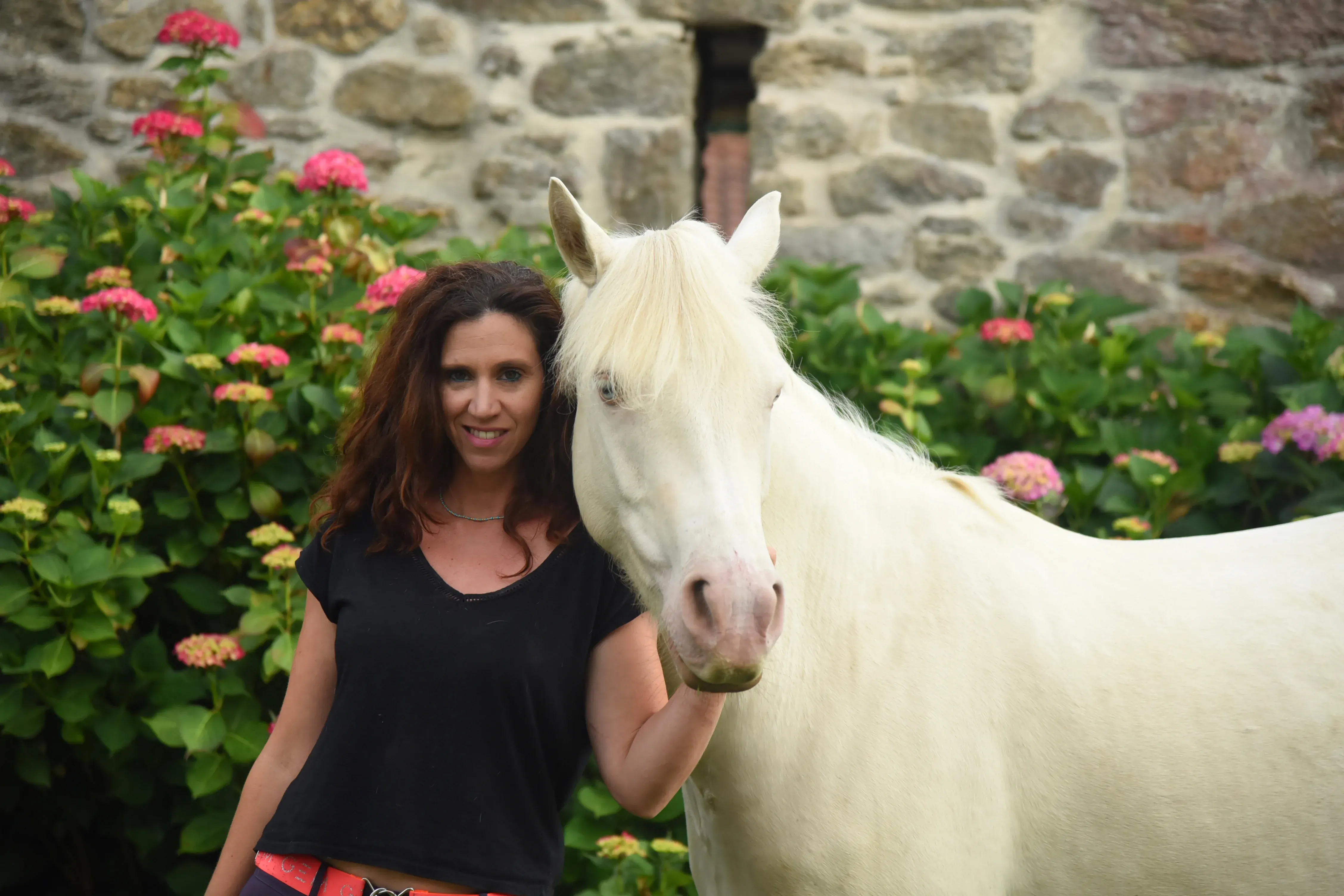 Laure aux côtés d’un cheval dans un cadre naturel